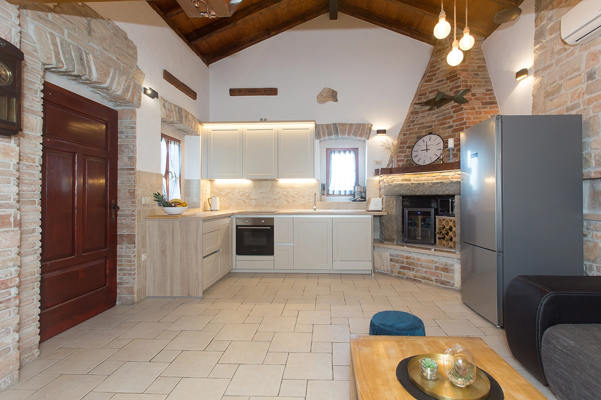 White kitchen with wooden brown entrance doors to the house and a refrigerator in the kitchen.